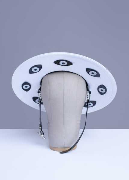 Apatico harness hat with wide brim. Black and white two-tone faux strap. Eyeball design all around the brim.