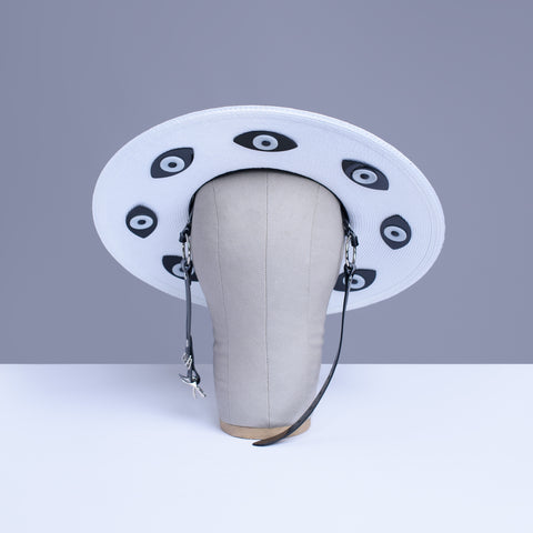 Apatico harness hat with wide brim. Black and white two-tone faux strap. Eyeball design all around the brim.