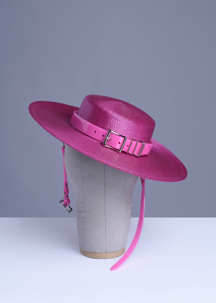 Fuchsia magenta pink harness hat with pink buckle band, displayed on a wig stand.