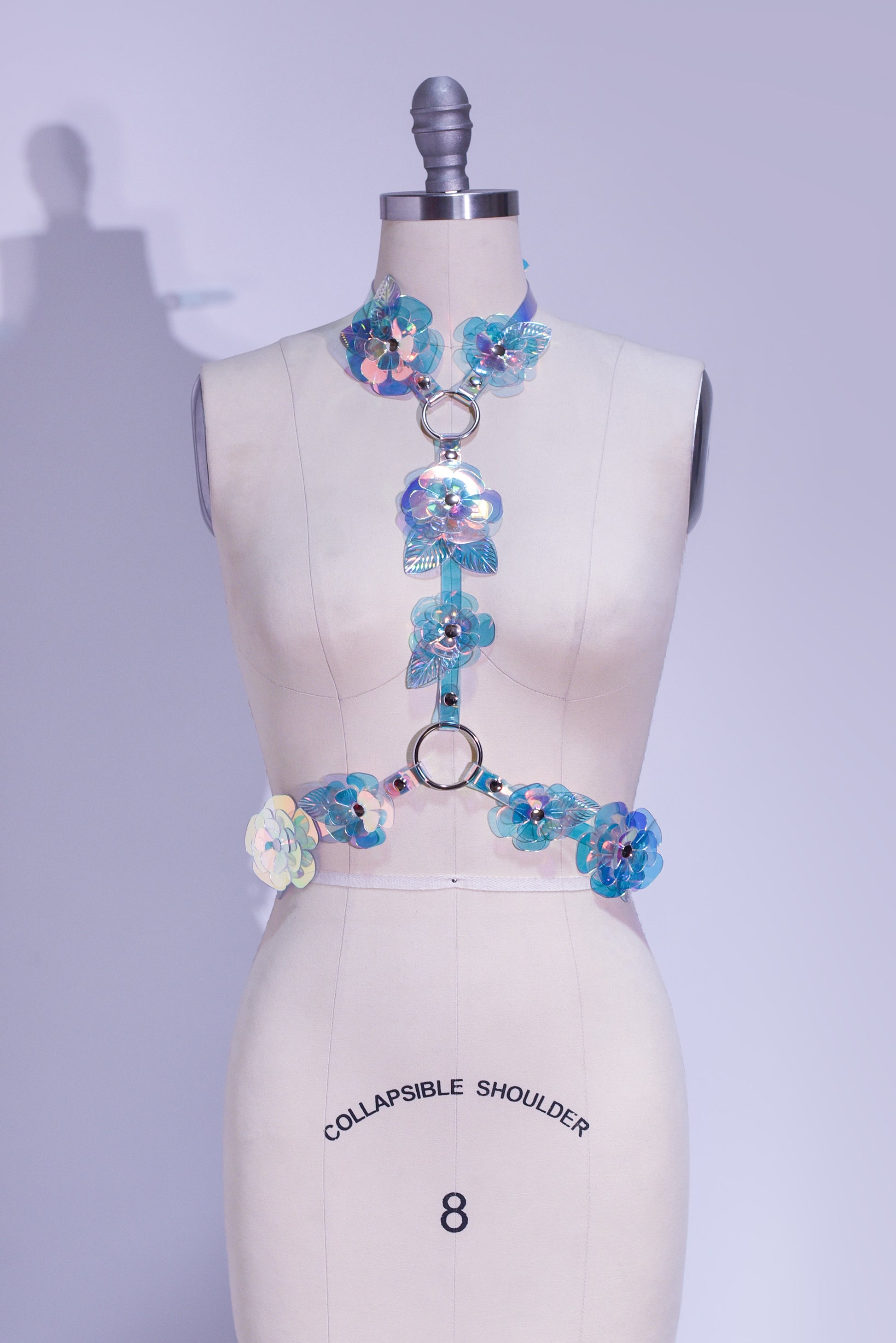 Rainbow, iridescent, holographic roses fashion  harness. Ornate, sculptural, three-dimentional floral harness displayed on a professional dressform.