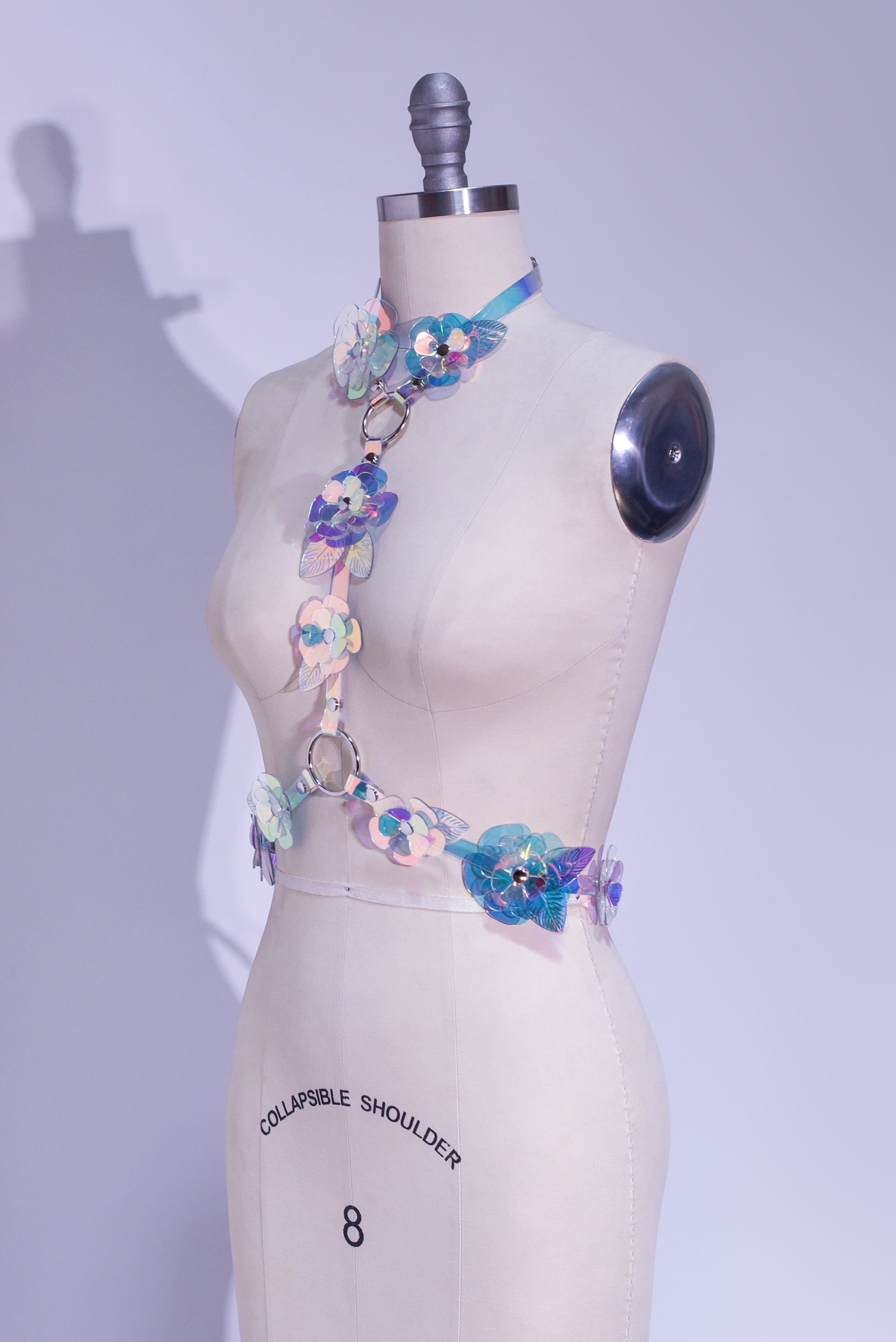 Rainbow, iridescent, holographic roses fashion  harness. Ornate, sculptural, three-dimentional floral harness displayed on a professional dressform.