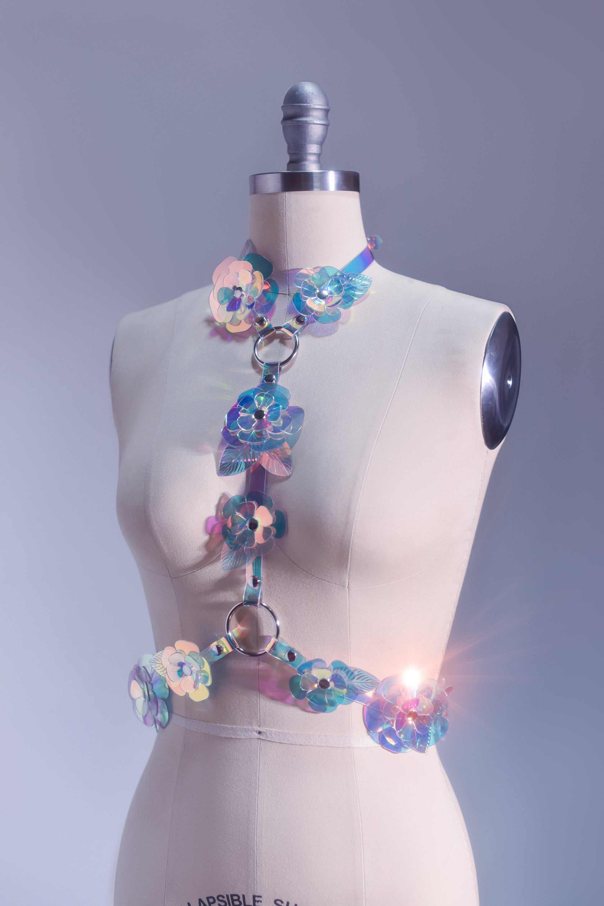 Rainbow, iridescent, holographic roses fashion  harness. Ornate, sculptural, three-dimentional floral harness displayed on a professional dressform.