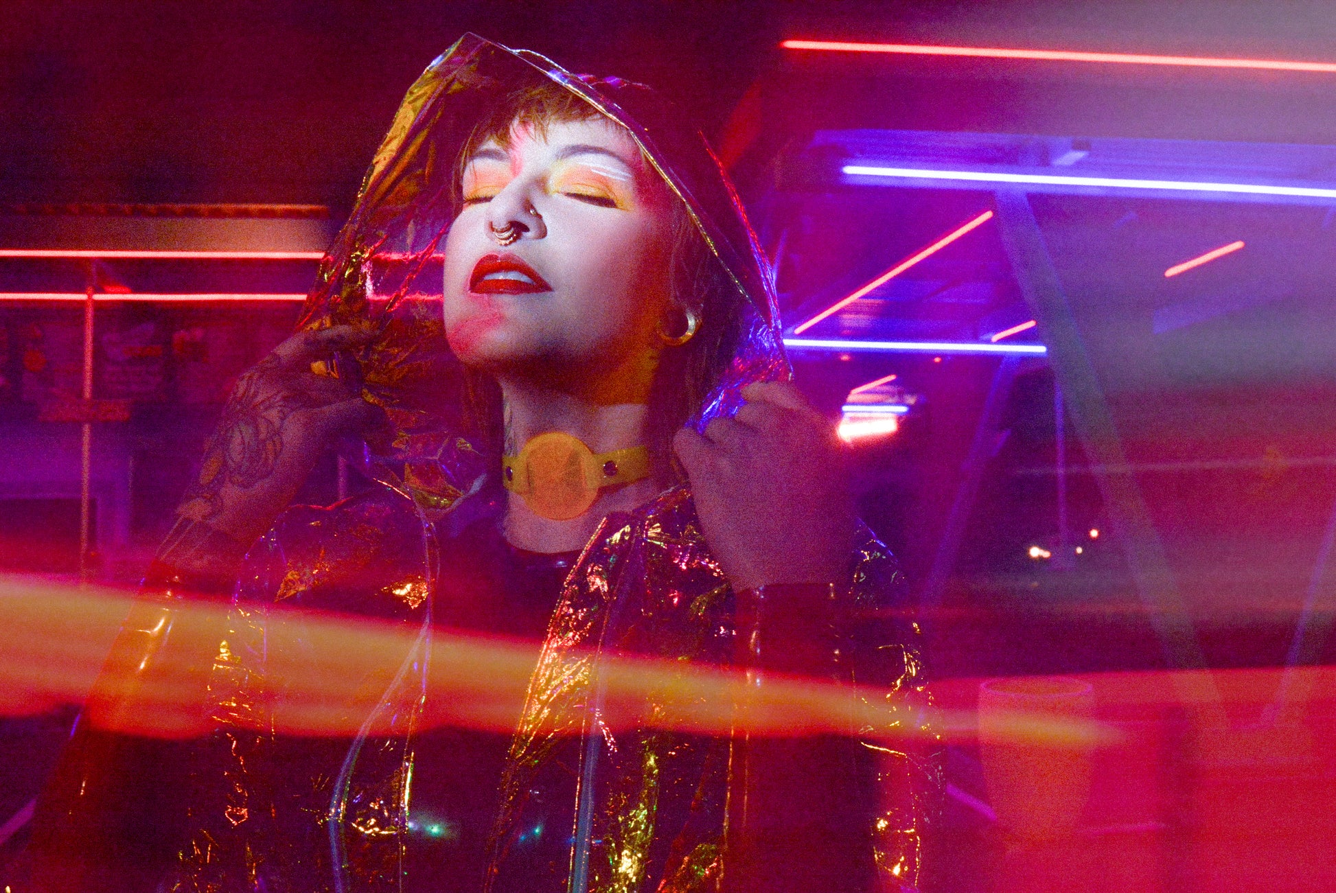 Katrina models a neon uv yellow choker by Apatico and Anhedonie under blue and red neon lights at night.
