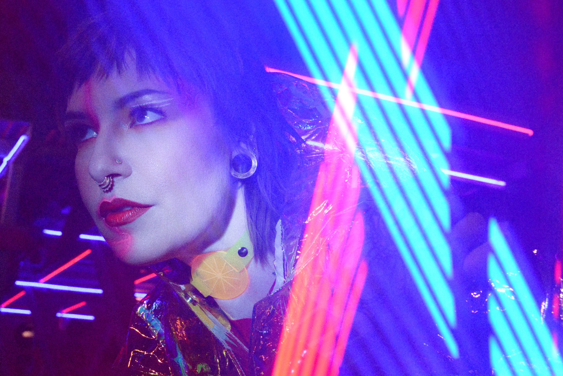 Katrina models a neon uv yellow choker by Apatico and Anhedonie under blue and red neon lights at night.