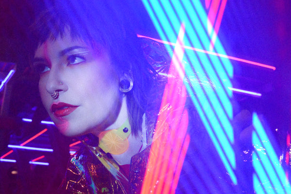 Katrina models a neon uv yellow choker by Apatico and Anhedonie under blue and red neon lights at night.