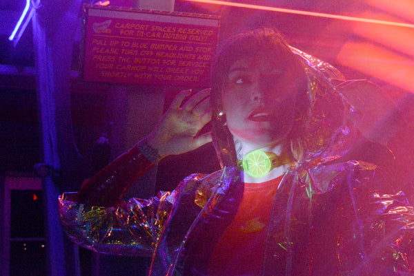 Katrina models a neon uv green choker by Apatico and Anhedonie under blue and red neon lights at night.