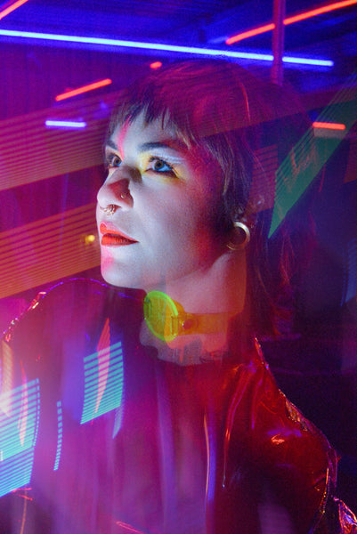 Katrina models a neon uv green choker by Apatico and Anhedonie under blue and red neon lights at night.