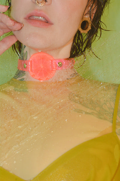 Katrina wears a neon pink choker by Apatico and Anhedonie while wearing a yellow latex top and yellow dress.
