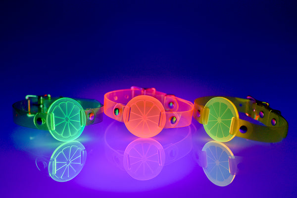 Three Apatico and Anhedonie choker collars in neon uv green, pink, and yellow with acrylic citrus centers.