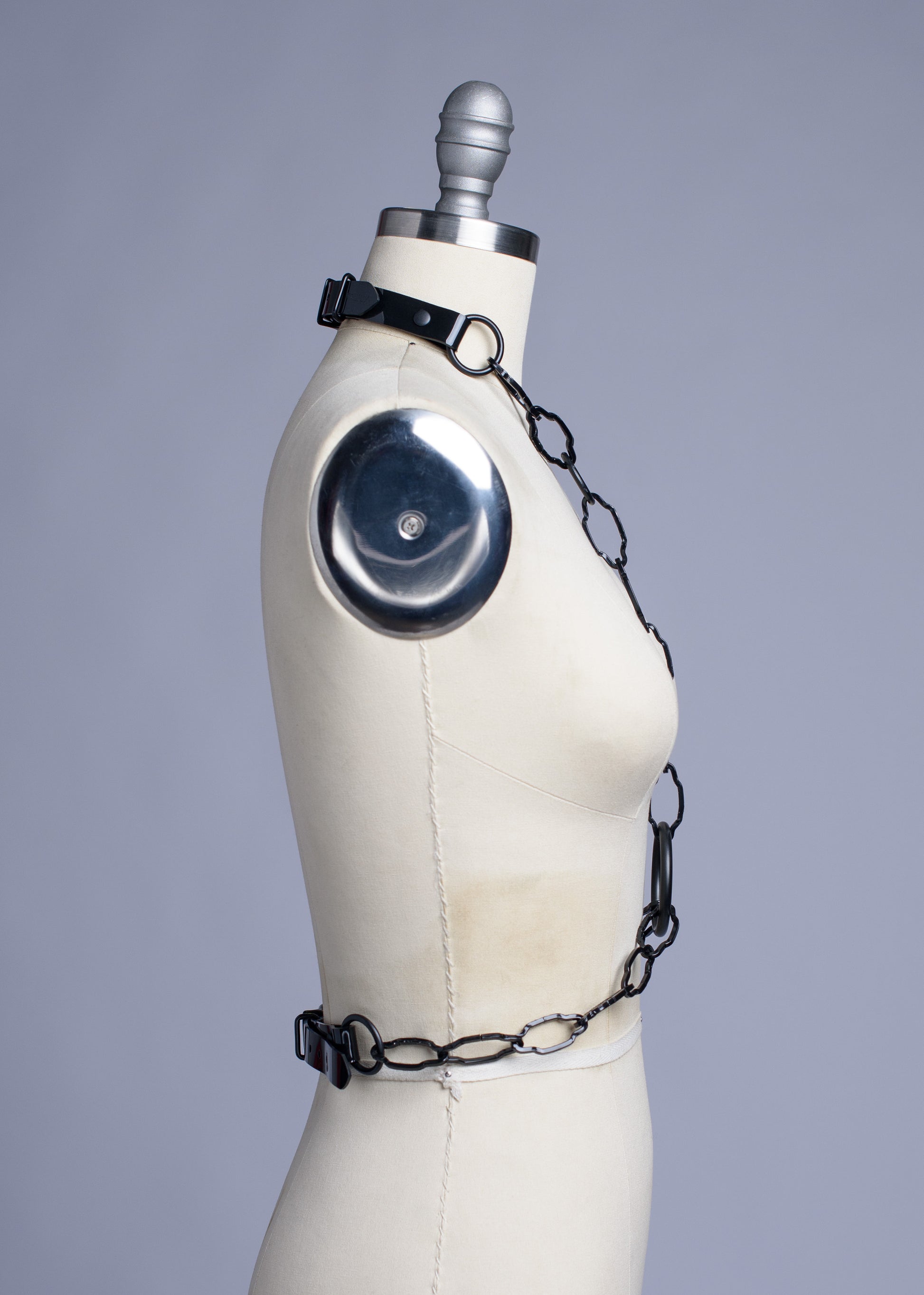 Black cathedral chain body harness belt displayed on a dress form.