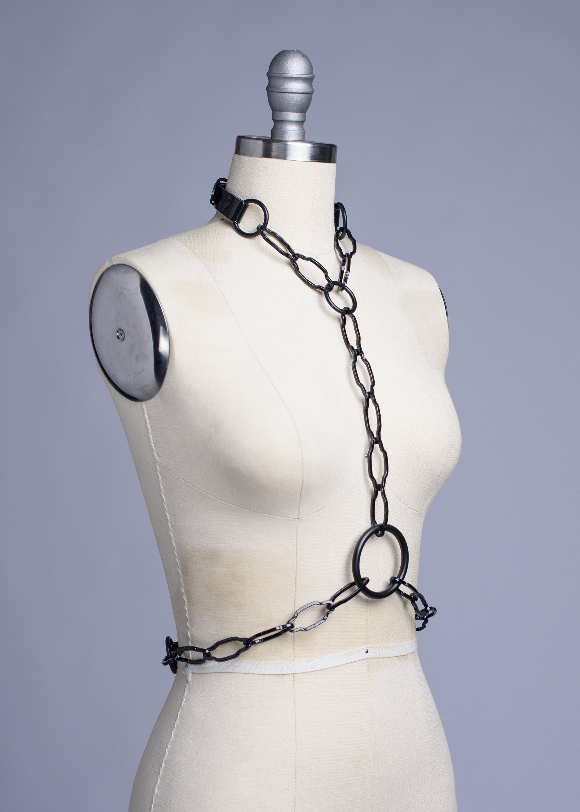 Black cathedral chain body harness belt displayed on a dress form.