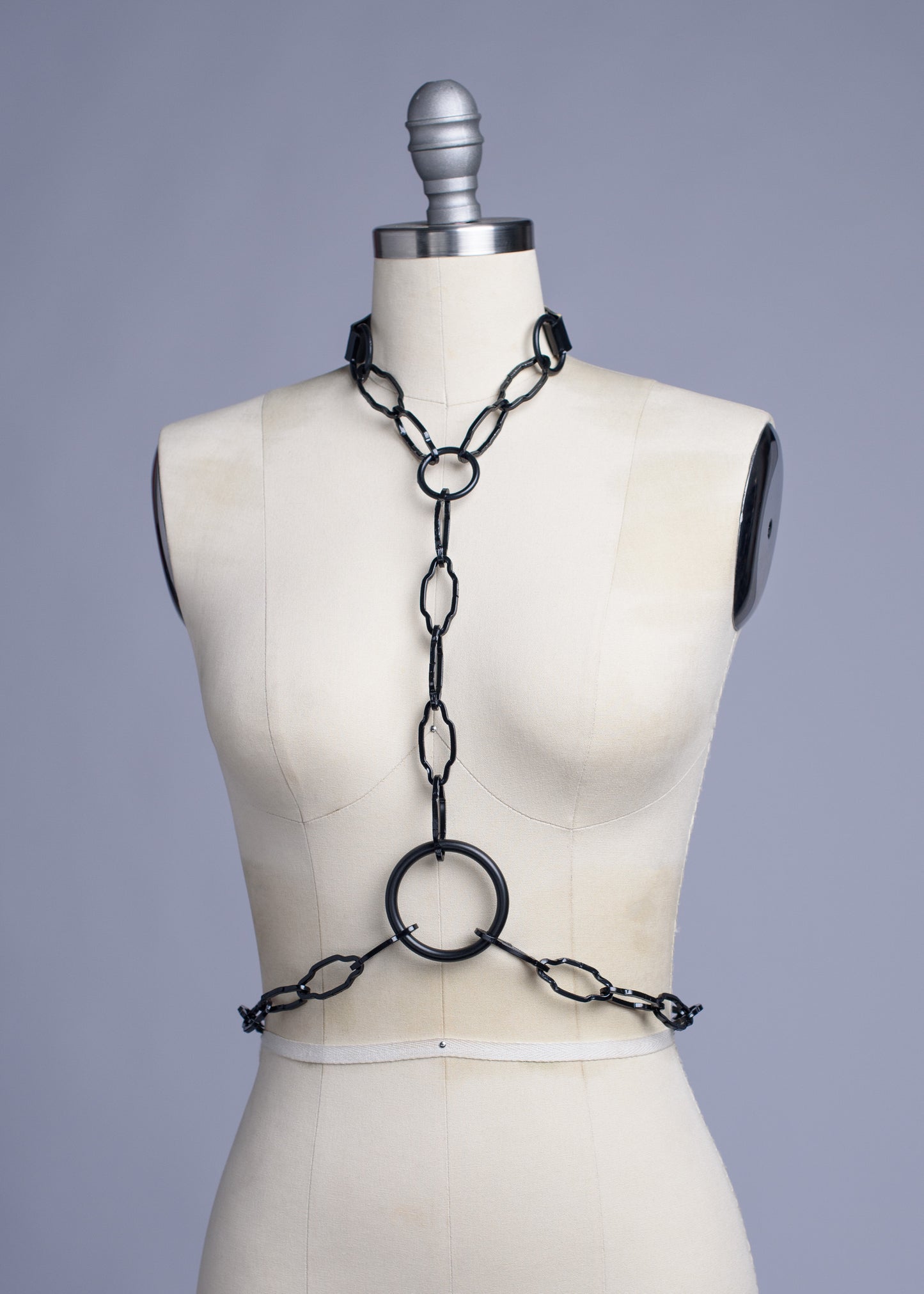 Black cathedral chain body harness belt displayed on a dress form.