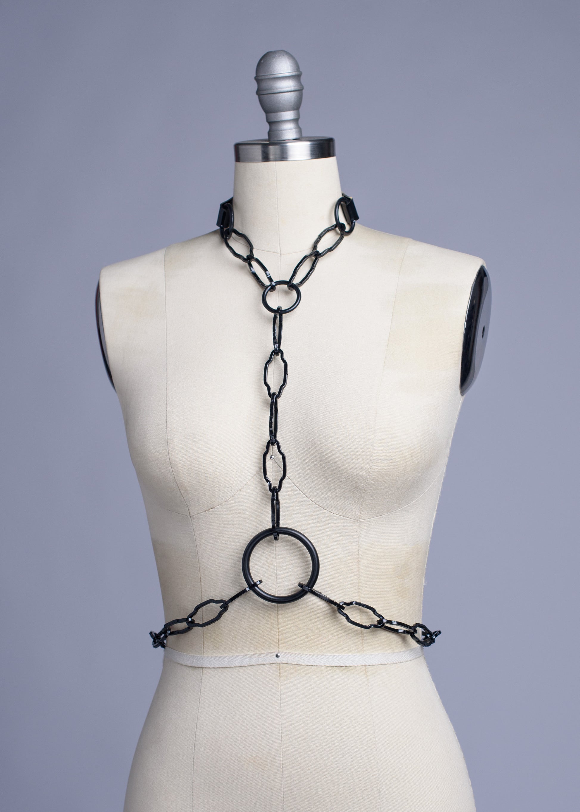 Black cathedral chain body harness belt displayed on a dress form.