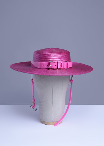 Fuchsia magenta pink harness hat with pink buckle band, displayed on a wig stand.