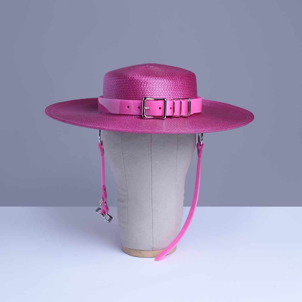 Fuchsia magenta pink harness hat with pink buckle band, displayed on a wig stand.