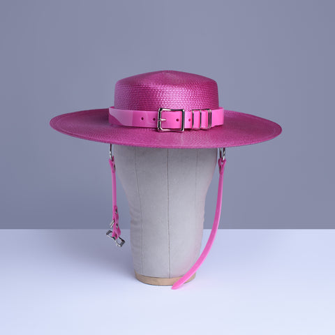 Fuchsia magenta pink harness hat with pink buckle band, displayed on a wig stand.