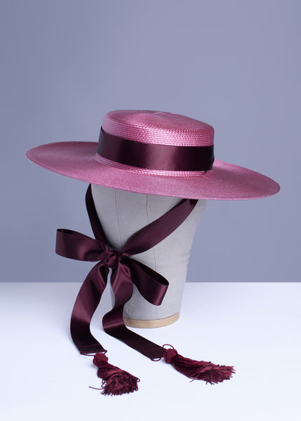 Apatico dusty mauve pink wide brim straw hat with burgundy satin ribbon ties and tassels.