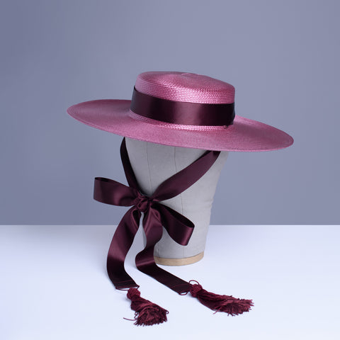 Apatico dusty mauve pink wide brim straw hat with burgundy satin ribbon ties and tassels.